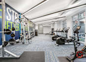 Thumbnail 43 of 87 - a gym with weights and cardio machines on the floor and a large wall of windows at Beekman on Broadway, Ann Arbor
