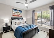 Thumbnail 6 of 48 - Modern bedroom with dark furniture and ceiling fan at Nalle Woods of Westlake Apartments, Austin, TX