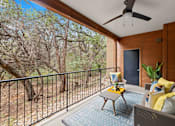 Thumbnail 10 of 48 - Covered patio with seating overlooking natural landscape at Nalle Woods of Westlake Apartments, Austin, TX