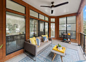Thumbnail 11 of 48 - Enclosed porch with modern furniture and ceiling fan at Nalle Woods of Westlake Apartments, Austin, 78746