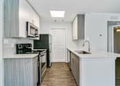 Thumbnail 28 of 29 - A kitchen with a black refrigerator and stove.