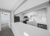 Thumbnail 22 of 37 - a white kitchen with a white counter top and black appliances