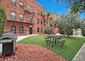 Thumbnail 11 of 20 - A brick building with a fire escape and a picnic table in front.