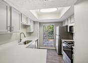 Thumbnail 16 of 35 - A modern kitchen with white cabinets and stainless steel appliances.