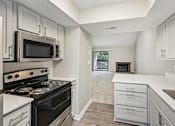 Thumbnail 17 of 35 - A kitchen with a black stove top oven and white cabinets.