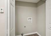 Thumbnail 14 of 35 - A white door is open to a small room with a light switch and a socket on the wall.