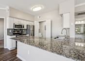 Thumbnail 49 of 54 - A kitchen with granite countertops and white cabinets.