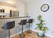 Thumbnail 15 of 21 - a kitchen with a bar with three stools and a potted plant