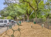 Thumbnail 10 of 41 - a dog park with trees and a fence and cars parked
