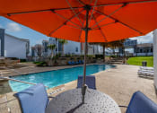 Thumbnail 9 of 37 - a pool with an orange umbrella over a table with chairs
