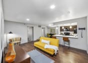 Thumbnail 22 of 37 - a living room with a yellow couch and a kitchen in the background