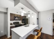 Thumbnail 20 of 37 - a kitchen with a white counter top and a white island with a sink and two chairs