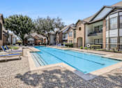 Thumbnail 22 of 54 - A swimming pool surrounded by apartment buildings and lounge chairs.