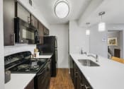 Thumbnail 19 of 37 - a kitchen with white countertops and black appliances