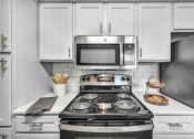Thumbnail 21 of 41 - a kitchen with white cabinets and a stove and a microwave