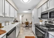 Thumbnail 22 of 41 - a kitchen with white cabinets and a stove and a microwave