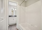 Thumbnail 49 of 58 - A white bathroom with a tub and a mirror.