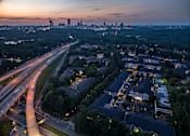 Thumbnail 18 of 80 - A cityscape at dusk with a highway running through it.