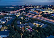 Thumbnail 21 of 80 - A nighttime aerial view of a city with a highway and buildings.