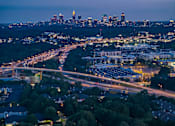 Thumbnail 22 of 80 - A cityscape at dusk with a highway running through it.