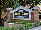 Thumbnail 27 of 80 - A sign for Arbor Gates at Buckhead, a rental community, is displayed in front of a brick wall and trees.