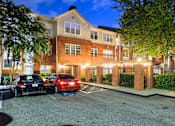Thumbnail 33 of 80 - A parking lot with cars parked in front of a brick building at night.