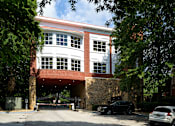 Thumbnail 37 of 80 - A car is parked in front of a building with a red brick archway.