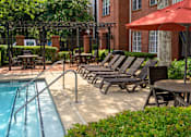 Thumbnail 6 of 80 - A pool with a red umbrella and chairs around it.