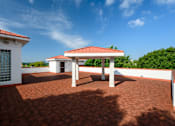Thumbnail 58 of 80 - A patio with a red roof and a white building with a window and a door.