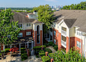 Thumbnail 59 of 80 - A swimming pool is surrounded by a patio and bushes in a residential area.