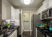 Thumbnail 9 of 80 - A kitchen with a black counter top and white cabinets.