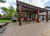 Thumbnail 1 of 14 - A wooden pergola with red chairs and a stone patio.