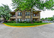 Thumbnail 8 of 14 - A large apartment complex with a parking lot in front.