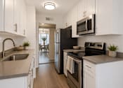 Thumbnail 7 of 15 - A kitchen with black appliances and white cabinets.