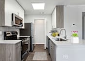 Thumbnail 20 of 29 - A modern kitchen with a refrigerator, microwave, oven, and sink.