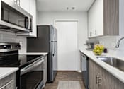 Thumbnail 27 of 29 - A modern kitchen with black appliances and wooden cabinets.