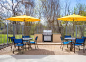 Thumbnail 13 of 16 - a patio with yellow umbrellas and tables with chairs and a grill at The Hudson, Texas ?