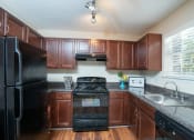 Thumbnail 20 of 23 - a kitchen with black appliances and wooden cabinets at Radbourne Lake Apartments, North Carolina, 28269