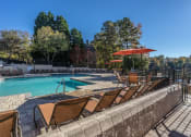 Thumbnail 14 of 23 - a swimming pool with chairs and umbrellas on a sunny day at Radbourne Lake Apartments, Charlotte, NC 28269 ?