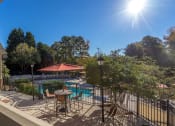 Thumbnail 13 of 23 - a patio with tables and chairs and a swimming pool at Radbourne Lake Apartments, North Carolina, 28269