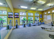 Thumbnail 9 of 20 - spacious gym with cardio equipment and windows at the estates apartments at Stone Creek at Old Farm Apartments, Texas