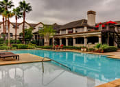 Thumbnail 20 of 20 - a swimming pool with a building in the background at Stone Creek at Old Farm Apartments, Houston, Texas