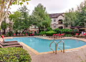 Thumbnail 1 of 20 - a swimming pool with chairs and trees and an apartment building in the background at Stone Creek at Old Farm Apartments, Houston, TX