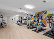 Thumbnail 26 of 27 - a gym with cardio equipment and a colorful wall