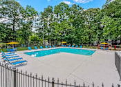 Thumbnail 22 of 27 - a swimming pool with chaise lounge chairs and trees in the background