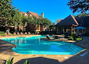 Thumbnail 10 of 14 - A swimming pool surrounded by lounge chairs and trees.
