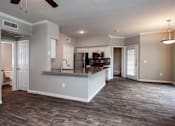 Thumbnail 3 of 14 - A spacious kitchen and living room with wood flooring and white walls.