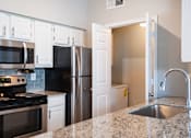 Thumbnail 6 of 14 - A kitchen with granite countertops and white cabinets.