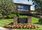 Thumbnail 1 of 18 - A sign for Woods at Addison with a phone number and a website.