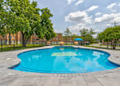 Thumbnail 10 of 12 - A round blue swimming pool surrounded by a black fence and trees.